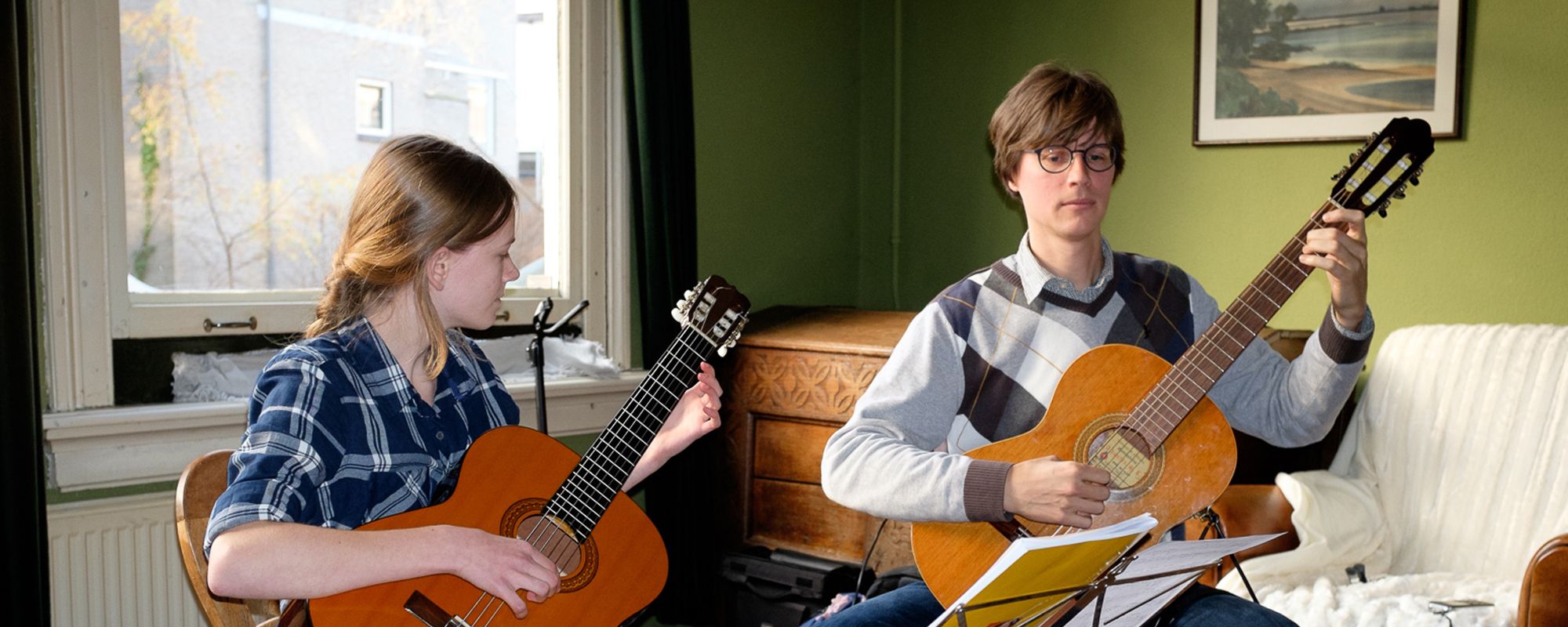 Gitaardocent en leerling spelen samen gitaar